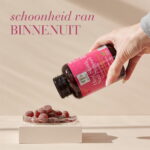 Hand giet Hair, Skin & Nail Support™ Gummies uit de verpakking met de tekst "schoonheid van binnenuit".
