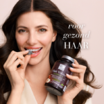 Vrouw eet een Hair Volume™ Gummies en houdt de verpakking vast met de tekst "voor gezond haar".