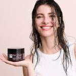 Vrouw met nat haar houdt Hair Volume™ Repair Mask vast, haar oogt glanzend en verzorgd