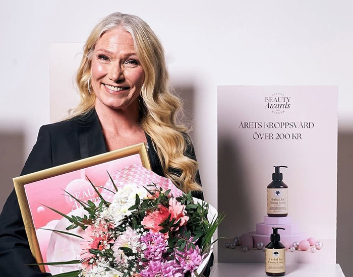 Vrouw houdt een boeket bloemen en een prijs vast en glimlacht.