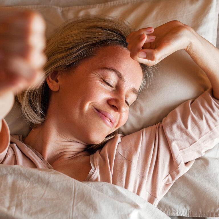 Vrouw rekt zich uit in bed tijdens haar ochtendroutine.