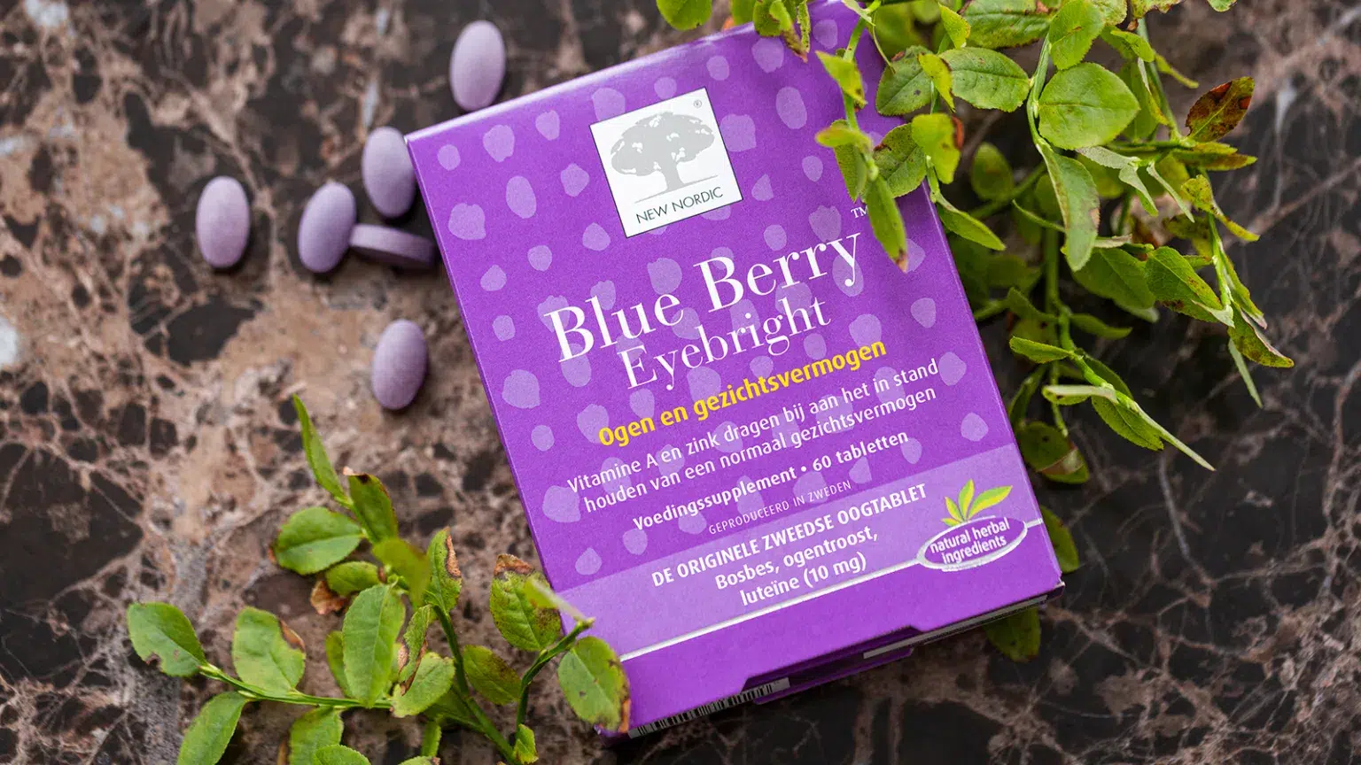 Blue Berry™ Eyebright verpakking met tabletten en bosbessentakken op een marmeren ondergrond.