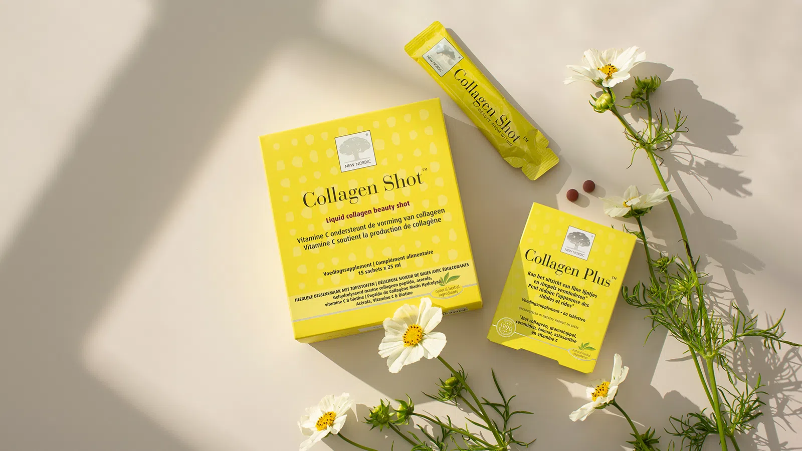 Collagen Shot™ en Collagen Plus™ assortiment met witte bloemen op een lichte achtergrond.
