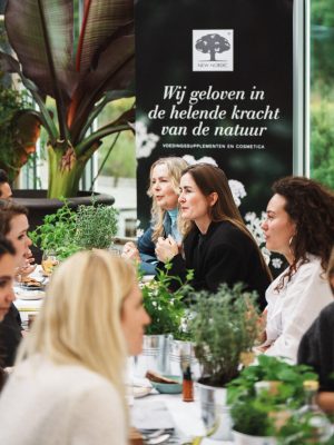 De helende kracht van de natuur – New Nordic-persevenement in Restaurant De kas 12 Deelnemers zitten samen aan tafel tijdens een New Nordic kruiden evenement met verse kruiden en planten.