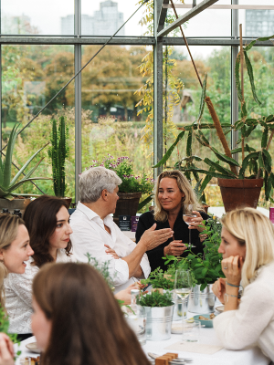 De helende kracht van de natuur – New Nordic-persevenement in Restaurant De kas 2 Deelnemers praten en genieten samen van een New Nordic kruiden evenement in een kasomgeving.